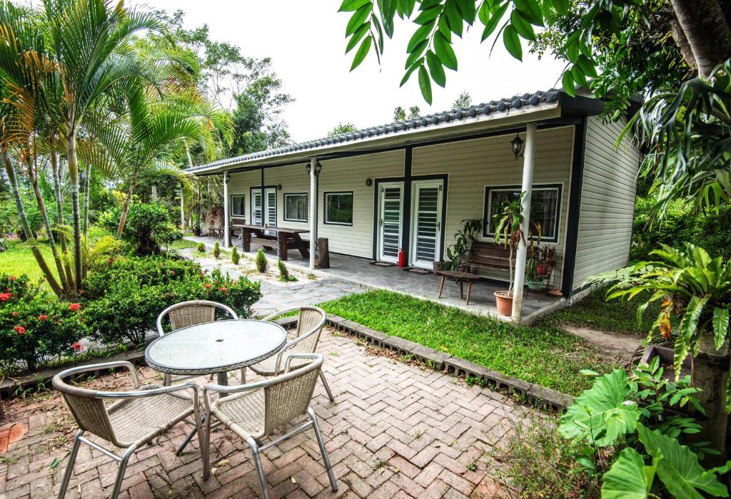 un patio con mesa y sillas frente a una casa en Deer Crossing B&B, en Longtian