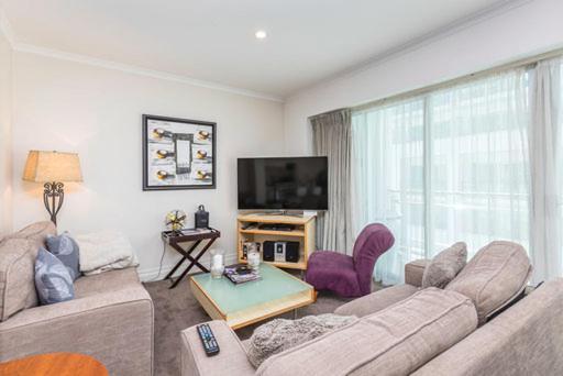 a living room with a couch and a tv at QV Spacious Apt on the Wharf with Wifi (797) in Auckland