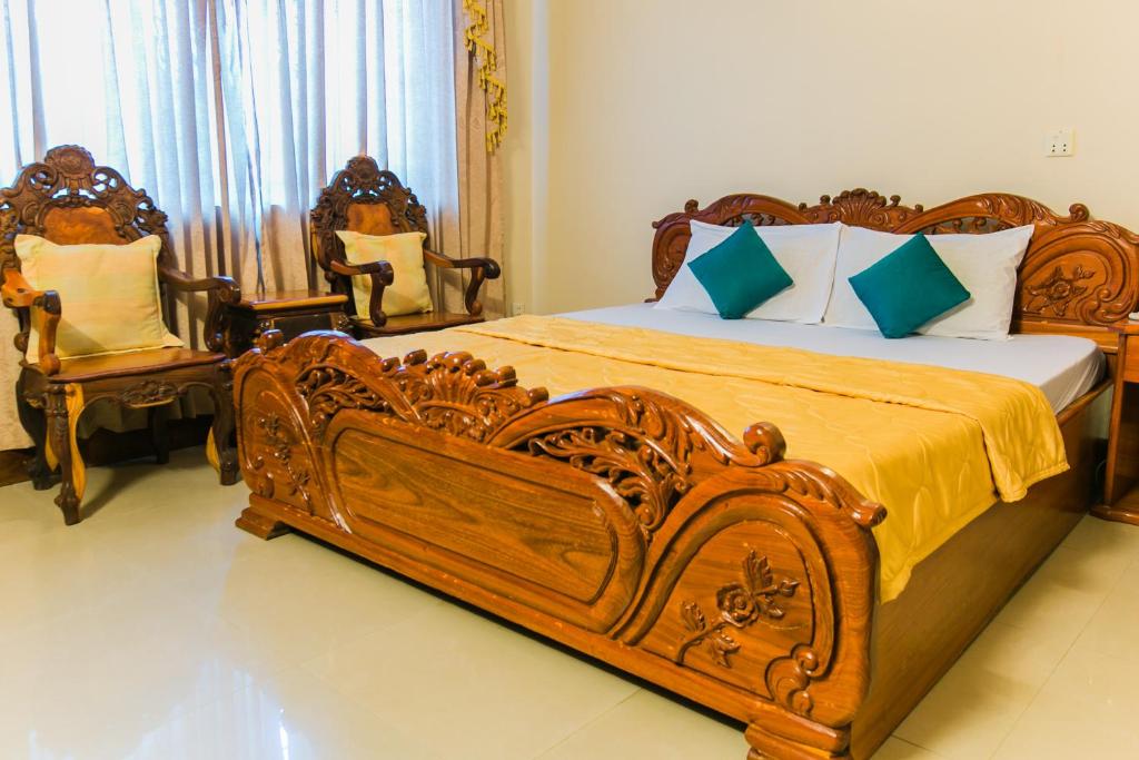 a bedroom with a large wooden bed and two chairs at Star Hotel in Battambang