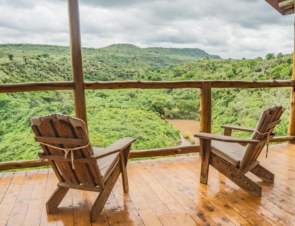 two chairs on a deck with a view of the mountains at Honeymoon Hut in Naivasha