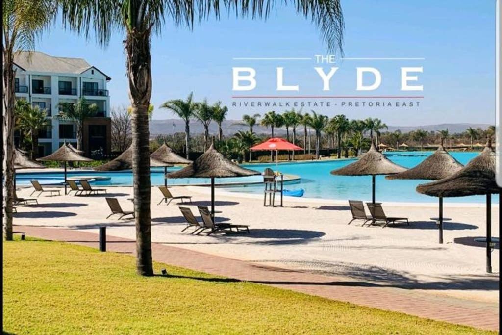 a resort with a pool and chairs and umbrellas at The Blyde, Crystal Lagoon One Bed Apartment. in Pretoria