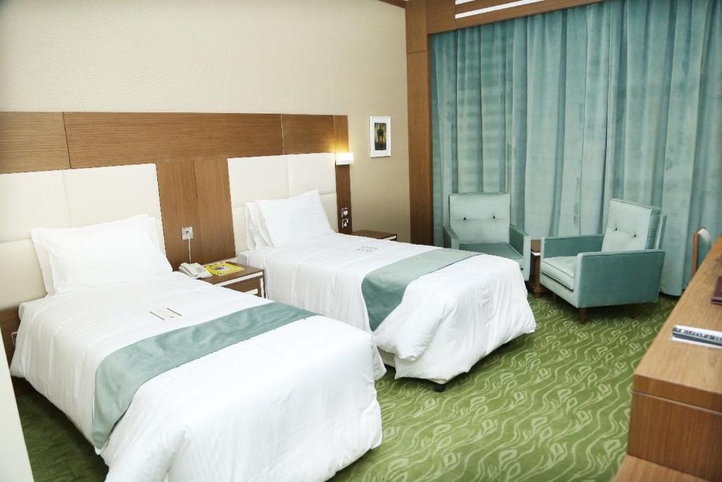 a hotel room with two beds and a desk at Ras Al Khaimah Hotel in Ras al Khaimah
