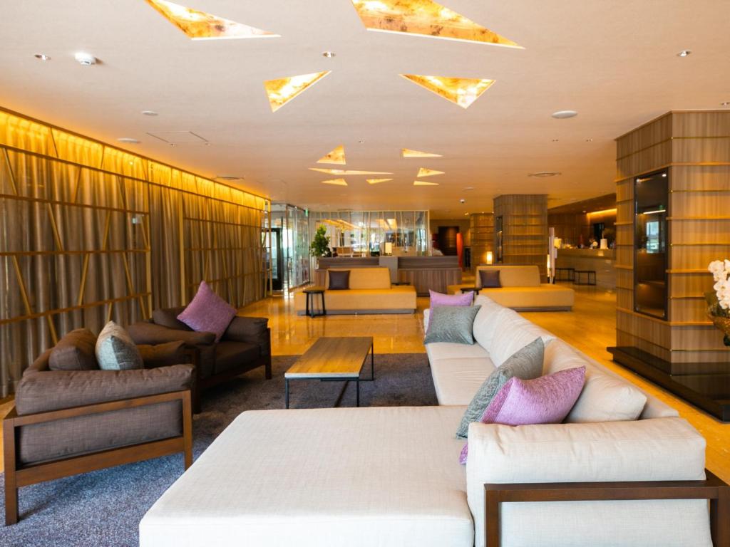 a lobby with couches and tables in a building at Maizuru Grand Hotel in Maizuru