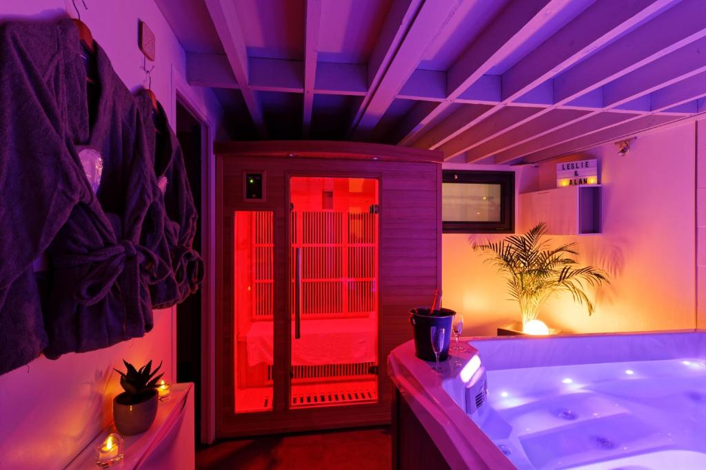 een paarse badkamer met een bad en een rood licht bij Romance Spa lofts haut de gamme avec sauna in Le Havre