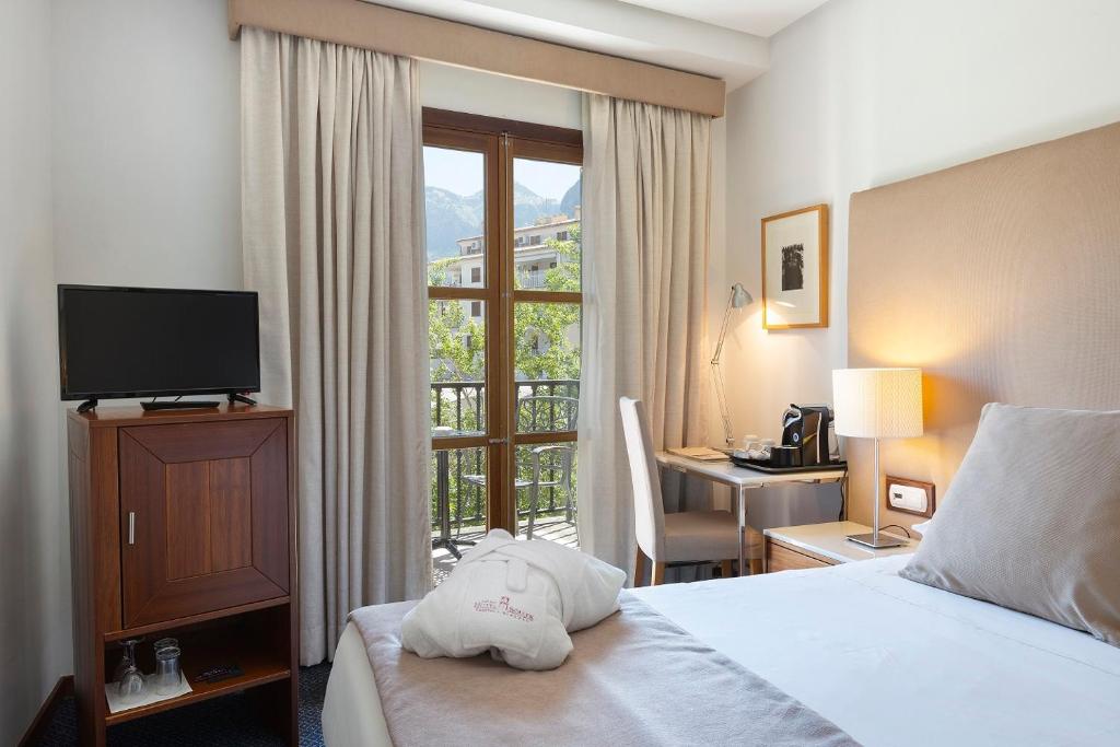 a hotel room with a bed and a desk and a window at Gran Hotel Soller in Sóller