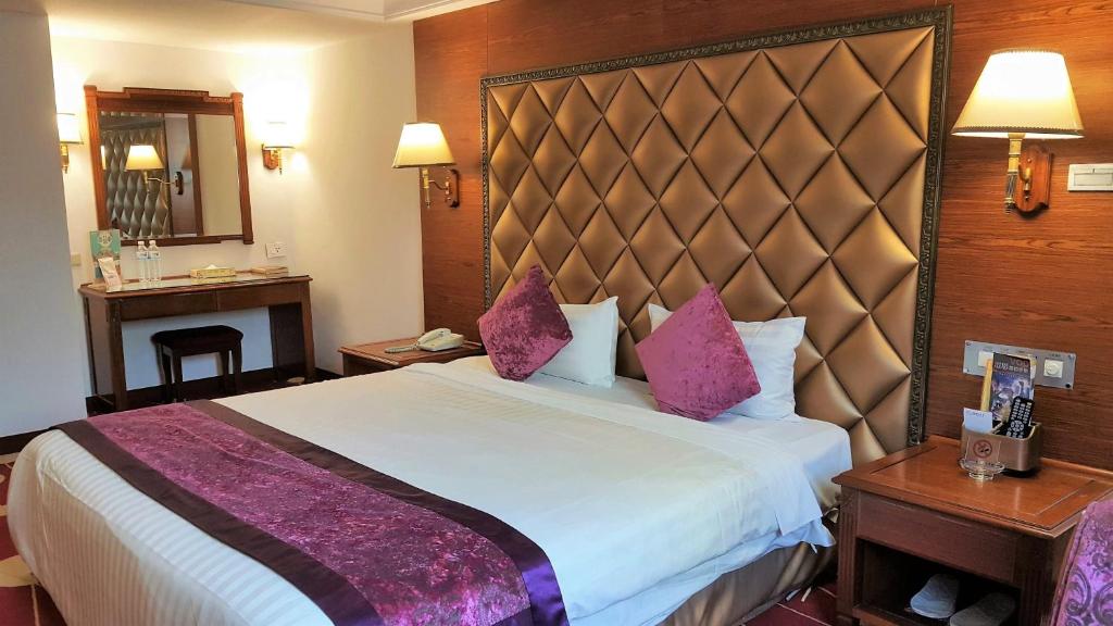 a hotel room with a large bed with purple pillows at Chyuan Du Spring Resort in Taipei