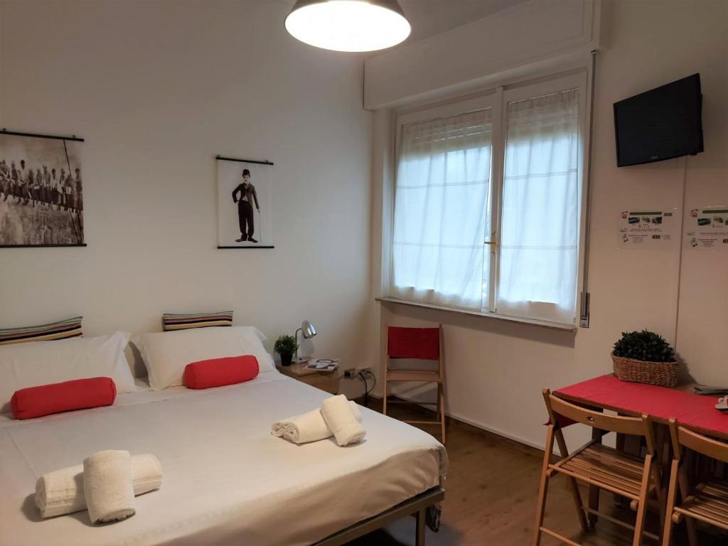 una camera da letto con due letti, un tavolo e una finestra di Bnbook-Ughelli a Rho