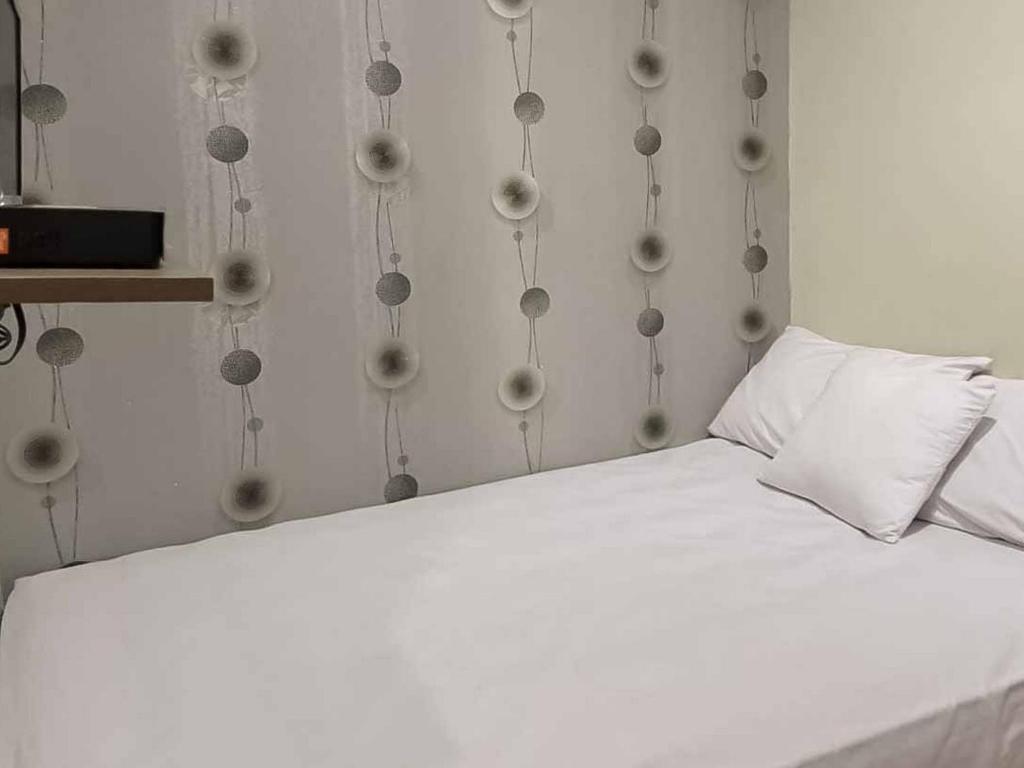 - un lit blanc dans une chambre dotée d'un mur avec des billes dans l'établissement Aimer Guest House Syariah Mitra RedDoorz, à Cilegon