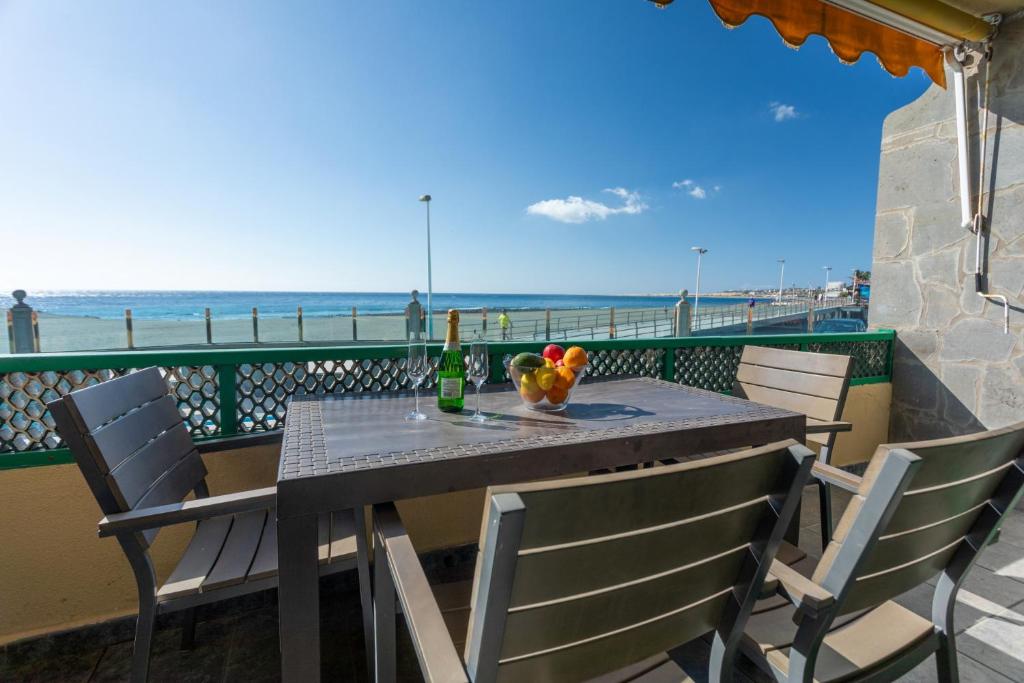 Una mesa y sillas en un balcón con la playa. en Las Burras Beach terrace&pool By CanariasGetaway, en San Agustín