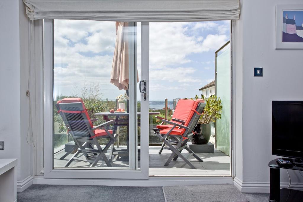 a sliding glass door leading to a patio with chairs at Blue Bay, Marazion in Perranuthnoe