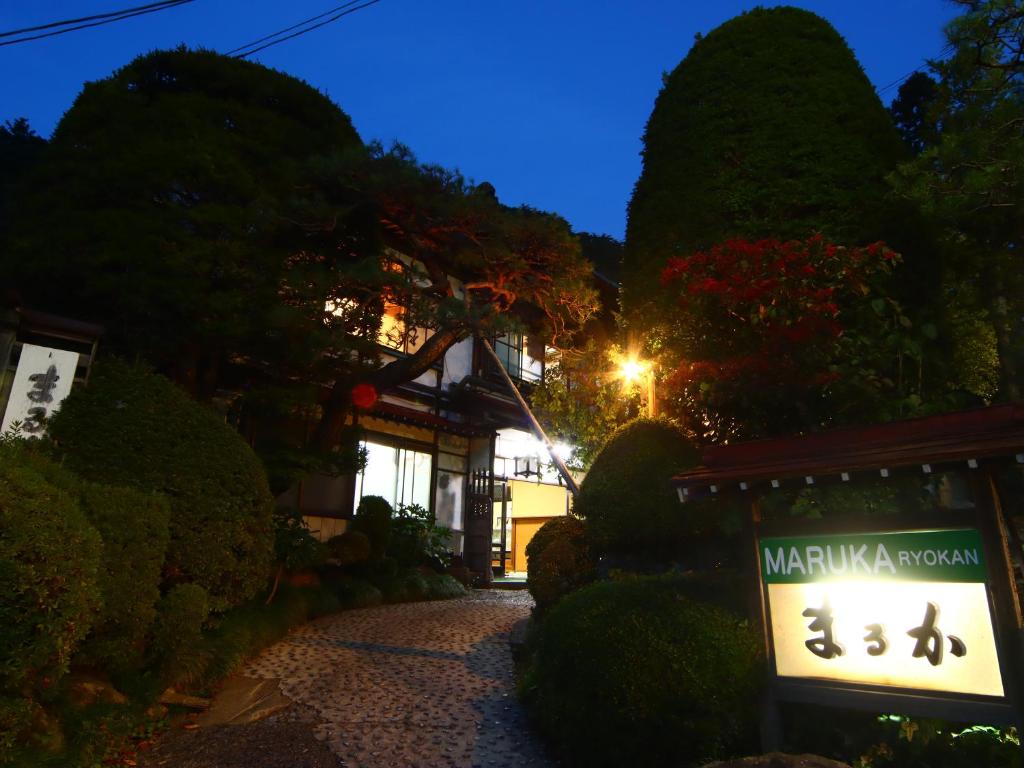 una señal frente a un edificio por la noche en Maruka Ryokan en Yamanouchi