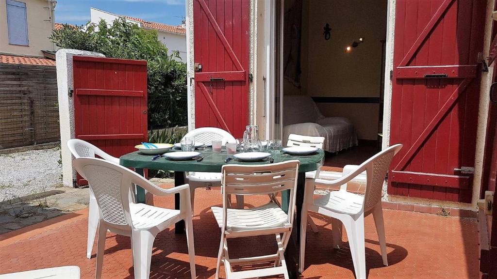 une table et des chaises avec une table verte et des portes rouges dans l'établissement Proche de la plage et des commerces joli pavillon 6 personnes-6VROUS5, à Saint Cyprien Plage
