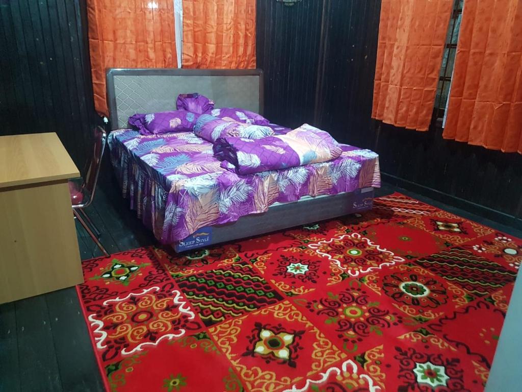 sypialnia z łóżkiem i czerwonym dywanem w obiekcie Mimi Guest House Syariah Pangkalan bun w mieście Pangkalan Bun