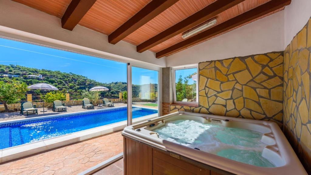 a bathroom with a tub and a swimming pool at Casa El Moral de Arenas by Ruralidays in Arenas