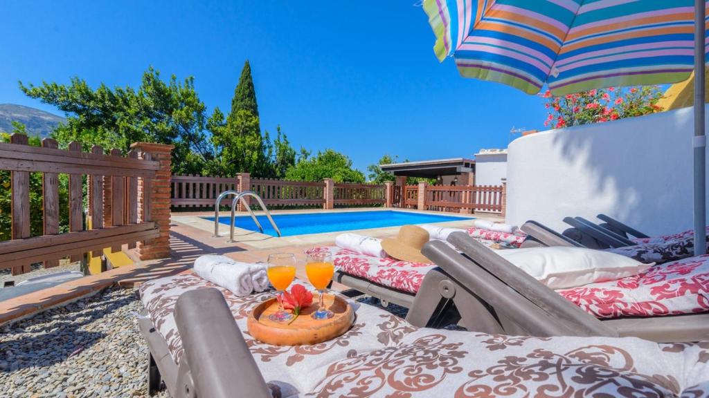 einen Hinterhof mit einem Pool mit Gartenmöbeln und einem Sonnenschirm in der Unterkunft Casa La Recacha Orgiva by Ruralidays in Órgiva