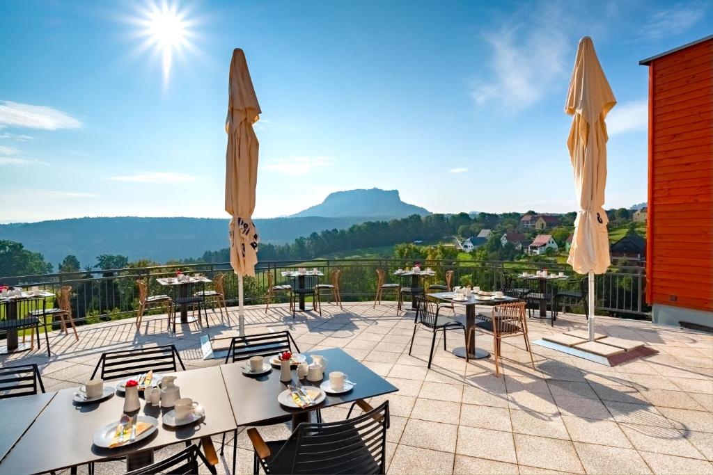 un patio con mesas y sillas y vistas. en Hotel Bei Gretel, Wellness & Ayurveda en Struppen-Siedlung