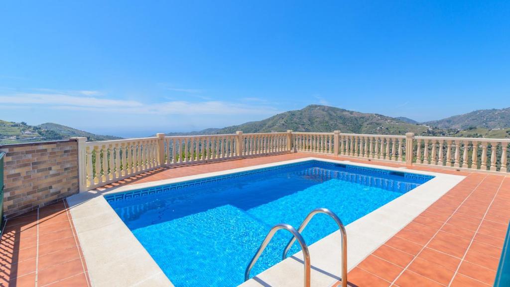 a swimming pool on a deck with mountains in the background at Cortijo Metomela Torrox by Ruralidays in Frigiliana