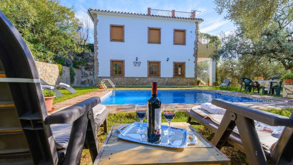 Una botella de vino sentada en una mesa junto a una piscina en Casa Ana Maria Periana by Ruralidays, en Periana