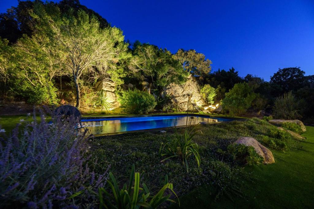 un homme debout à côté d'une piscine dans un jardin la nuit dans l'établissement Les Villas de Palombaggia, à Porto-Vecchio