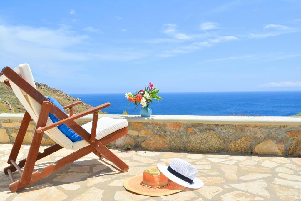 Panoramic Sea View Villa Saint Anna في كالو ليفادي: شخص يجلس على كرسي وله قبعة