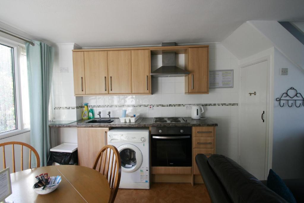a small kitchen with a stove and a dishwasher at Freshwater Bay Holiday Cottages in Pembroke