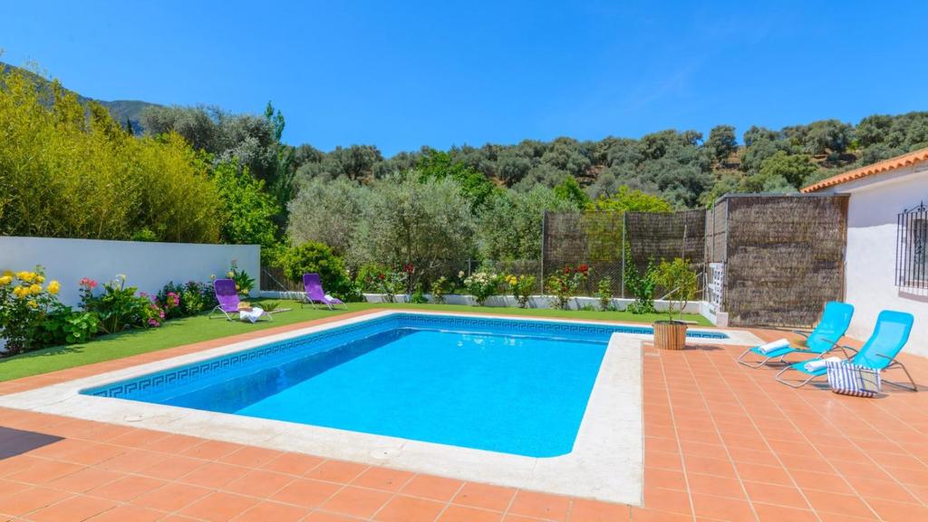 - une piscine dans un jardin avec deux chaises bleues dans l'établissement Cortijo Lalo Orgiva by Ruralidays, à Órgiva