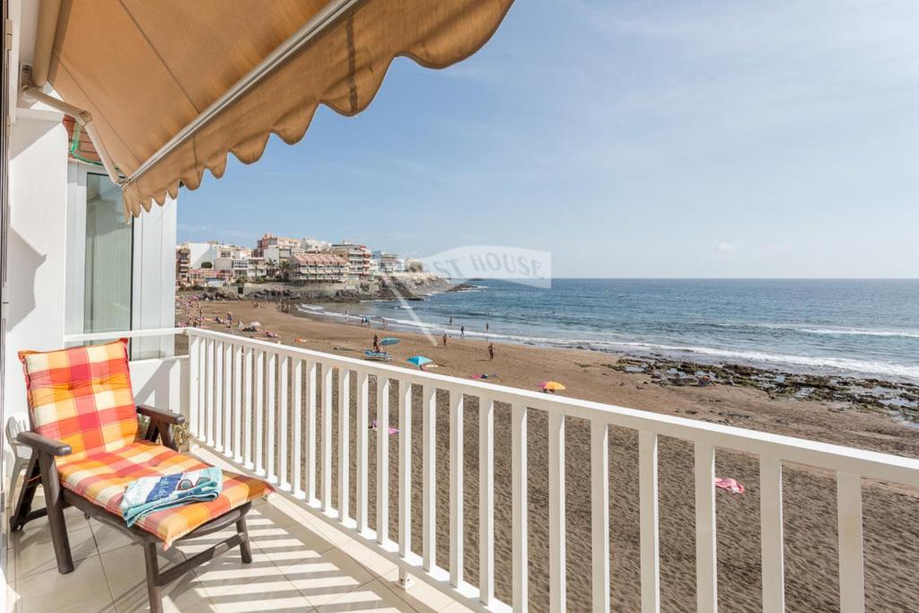 a balcony with a chair and a view of the beach at Luxury apartment in front of the beach in Melenara