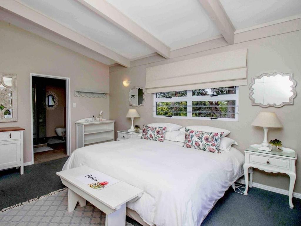 a bedroom with a large white bed and two tables at Cape Cottages in Bergvliet