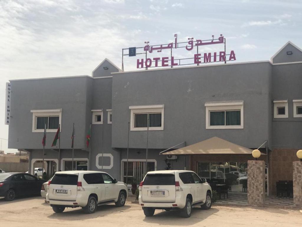 two cars parked in a parking lot in front of a hotel at Hotel Emira in Nouakchott