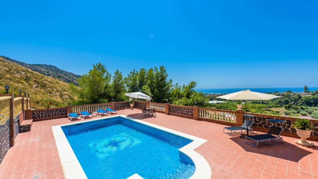 - une piscine sur une terrasse en briques avec des chaises et des parasols dans l'établissement Villa Martin Nerja by Ruralidays, à Nerja