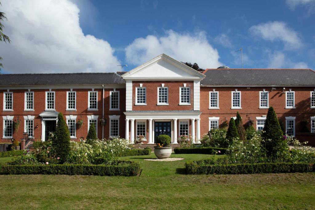 a large brick building with a garden in front of it at Manor Hotel Solihull, BW Signature Collection in Bickenhill