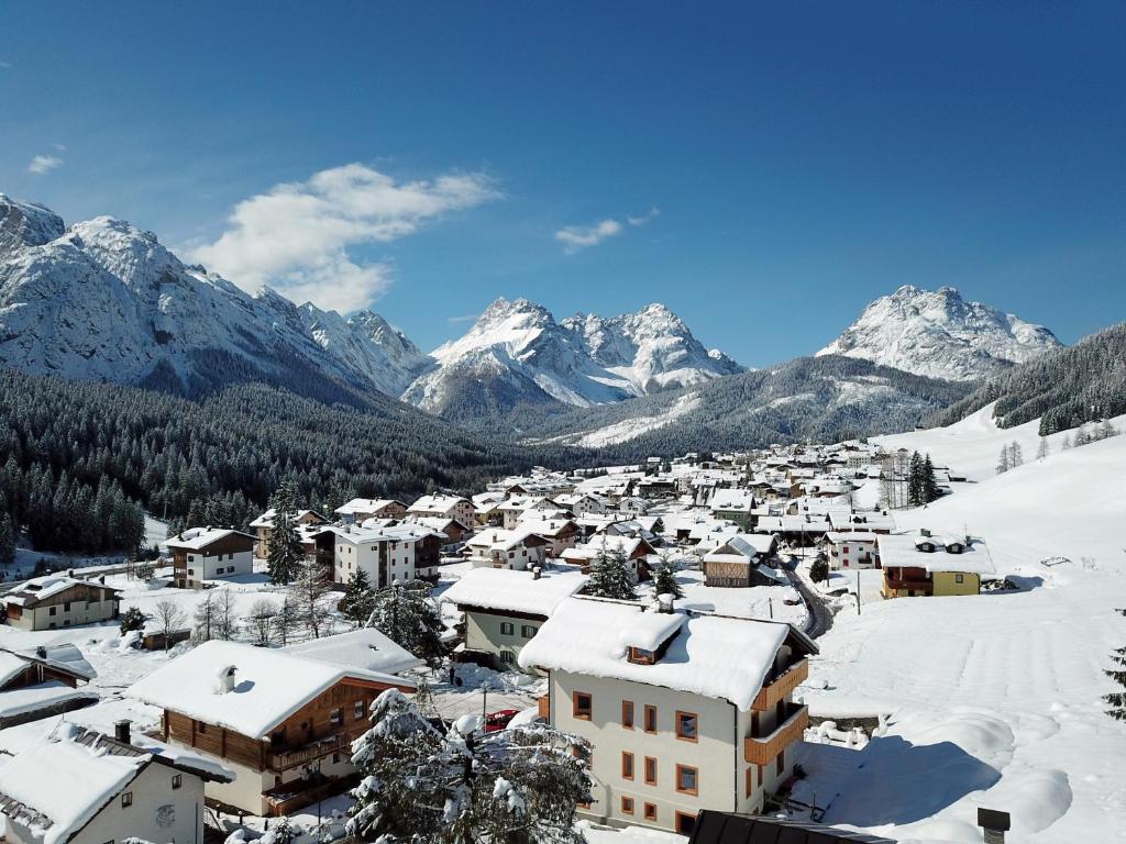 uma aldeia coberta de neve com montanhas ao fundo em Maison Boutique Fior d'Alpe em Sappada