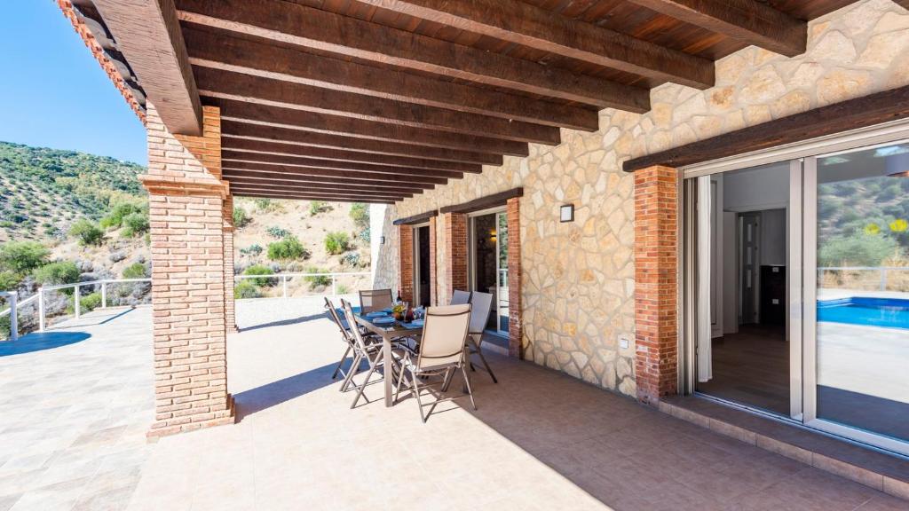 eine Terrasse eines Hauses mit einem Tisch und Stühlen in der Unterkunft Casa El Hoyillo El Gastor by Ruralidays in El Gastor