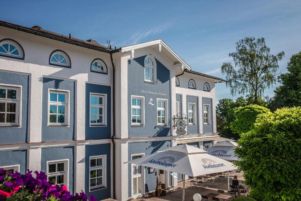 ein blau-weißes Gebäude mit einem Regenschirm in der Unterkunft Hotel Luitpold am See in Prien am Chiemsee