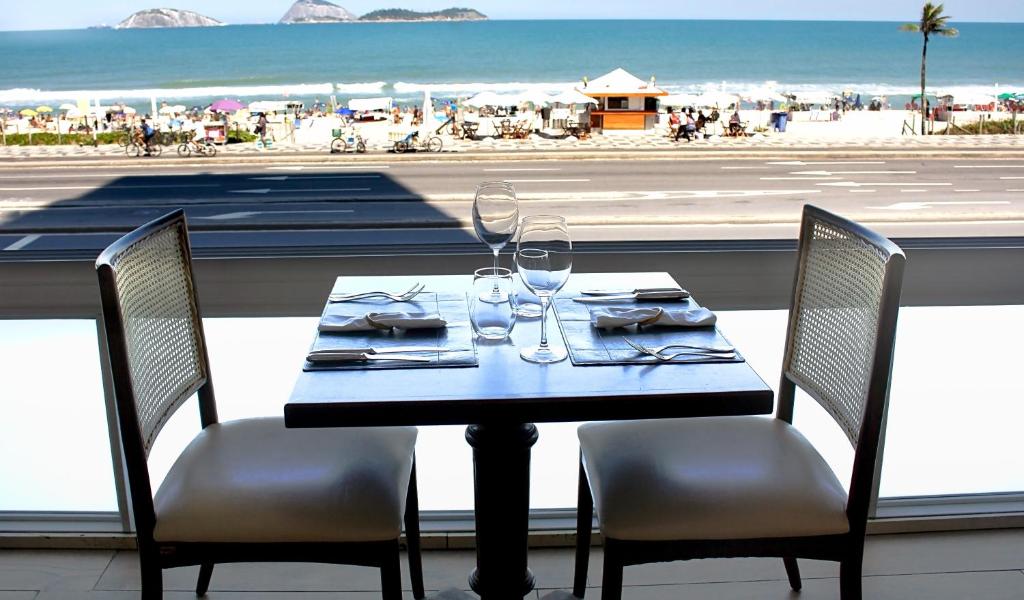 a table with two chairs and a table with wine glasses at Sol Ipanema Hotel in Rio de Janeiro