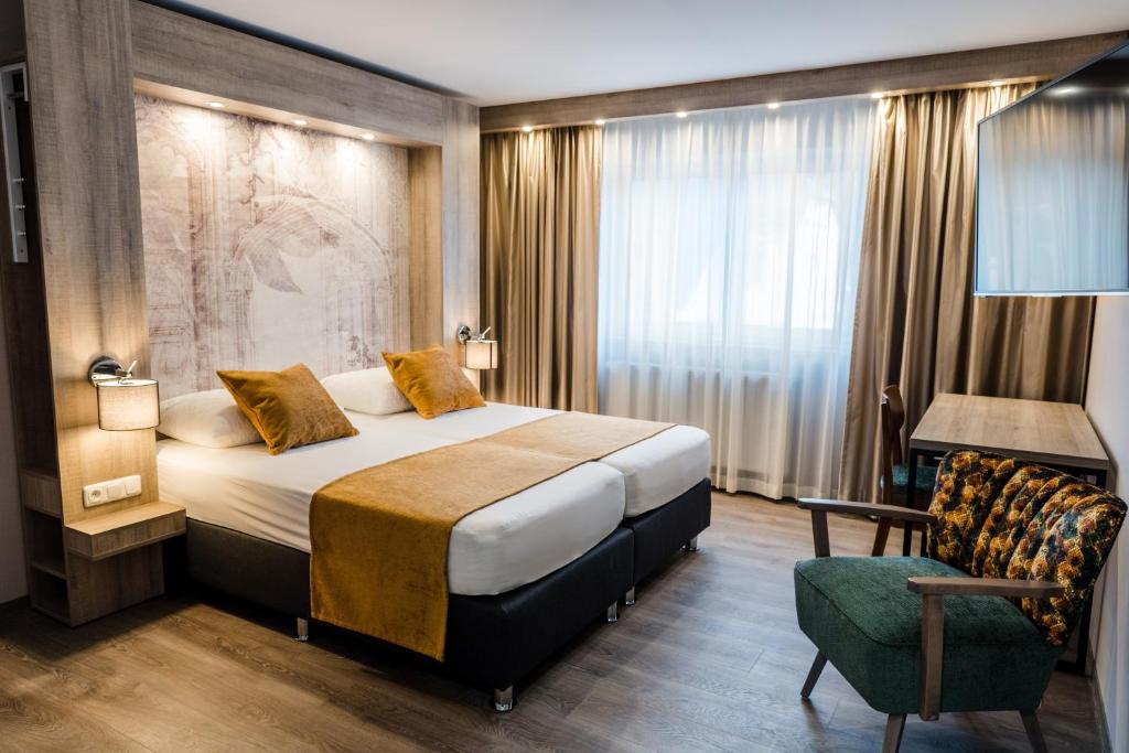 een hotelkamer met een bed en een stoel bij Liebig Hotel in Ehringshausen