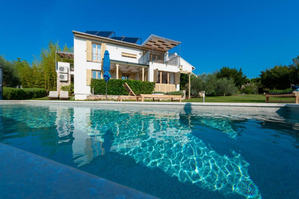 a villa with a swimming pool in front of a house at Casa Bamboo in Banjole