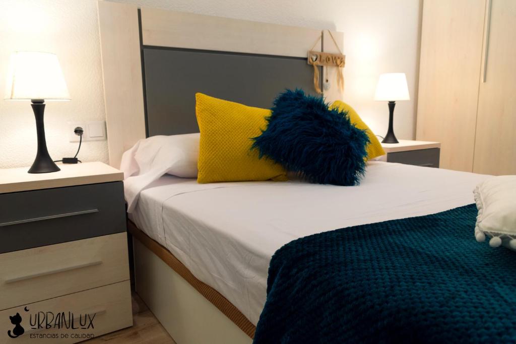 - une chambre avec un lit doté d'oreillers jaunes et bleus dans l'établissement UrbanLux Feria, à Albacete