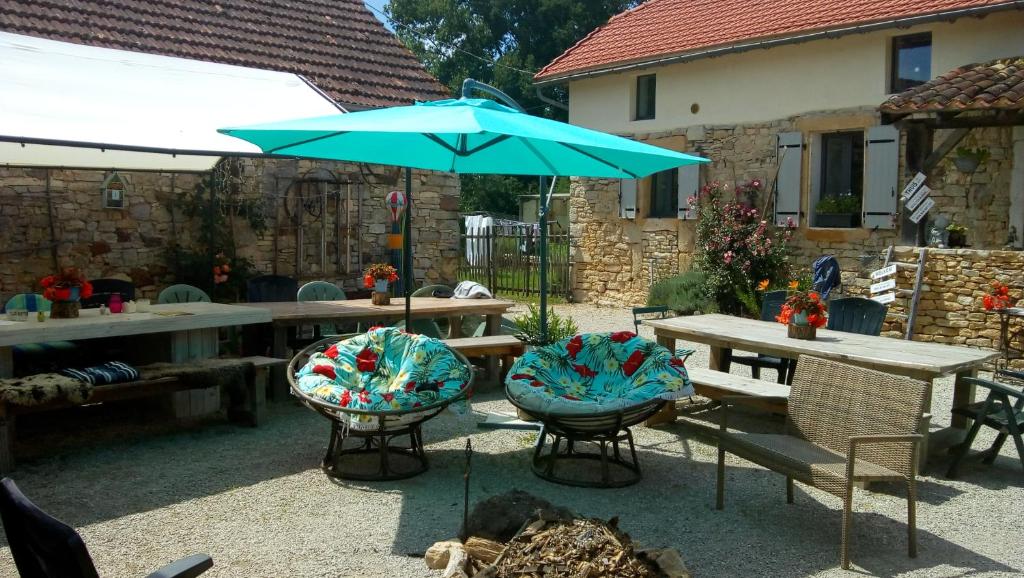 a picnic table with a blue umbrella and chairs at restyled bohemian mobil home la vie en rose in Montcléra