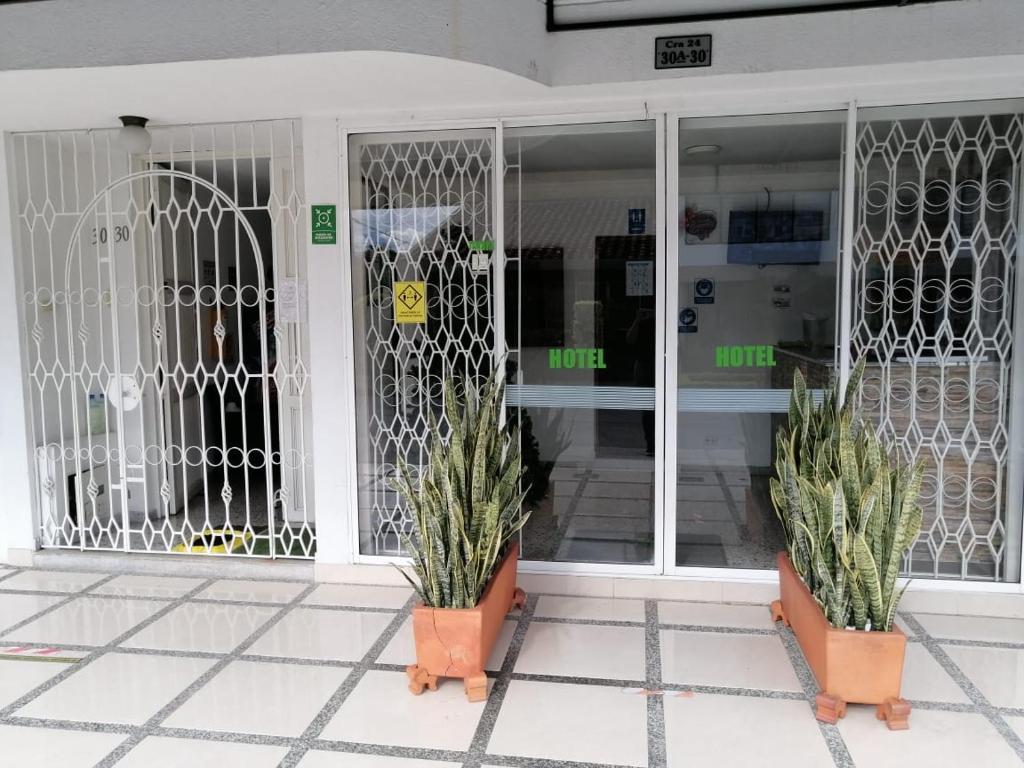 uma frente de loja com dois vasos de plantas na frente de uma porta em HOTEL DULCES SUEÑOS N°2 em Tuluá