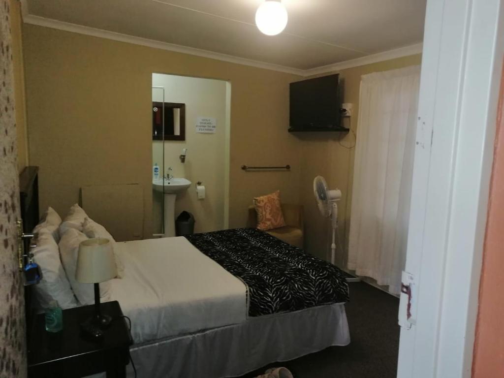 um quarto de hotel com uma cama e um lavatório em zig zag self catering accommodation em Ladysmith