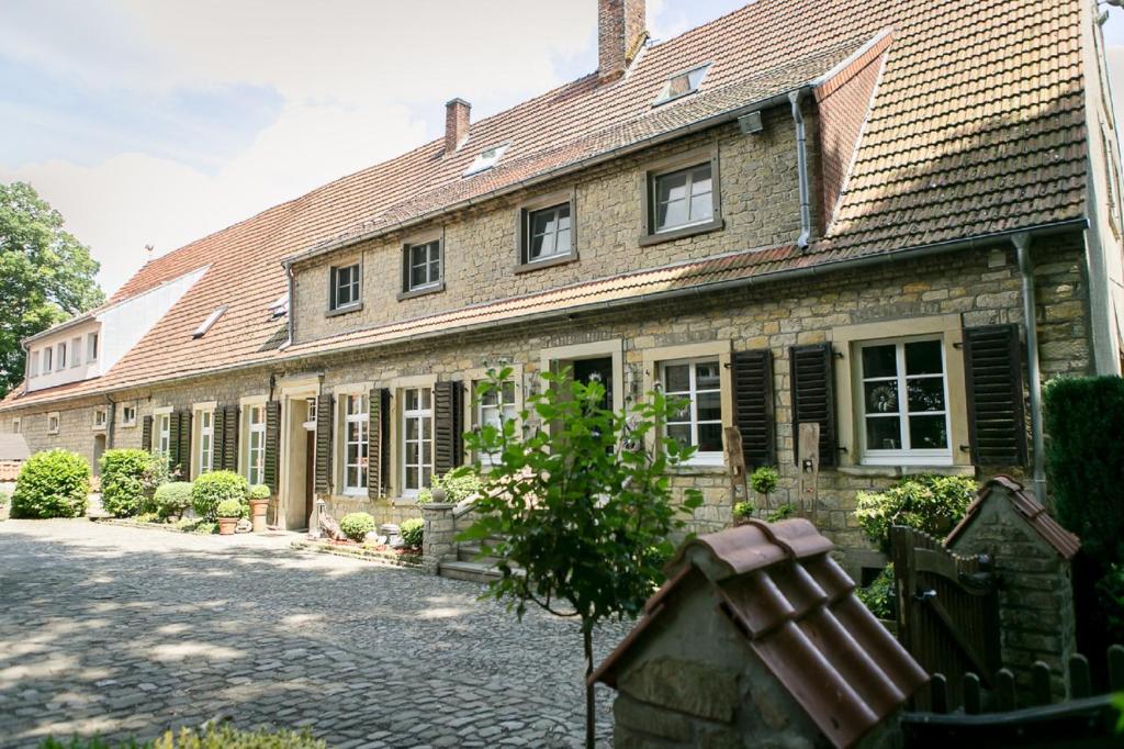 une vieille maison en pierre avec un arbre en face de celle-ci dans l'établissement Gutshof Schulze-Althoff, à Schöppingen