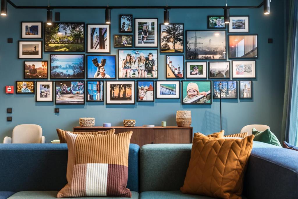 una sala de estar con una pared azul llena de cuadros. en Hotel einsmehr en Augsburg