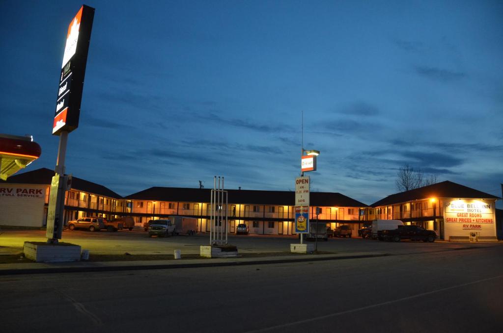 um edifício com carros estacionados num parque de estacionamento à noite em Blue Bell Inn em Fort Nelson