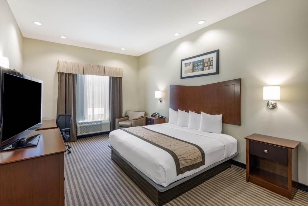 a hotel room with a bed and a flat screen tv at Baymont by Wyndham Victoria in Victoria