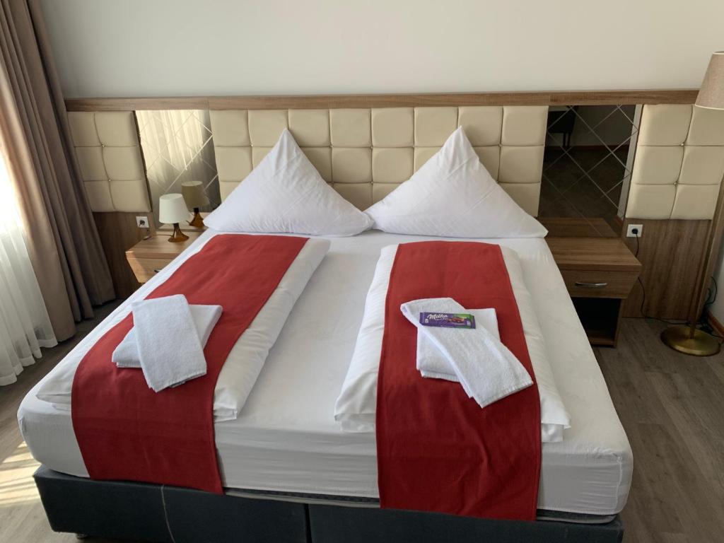uma cama com lençóis e toalhas vermelhos e brancos em Hotel Hausen Obertshausen Frankfurt em Obertshausen