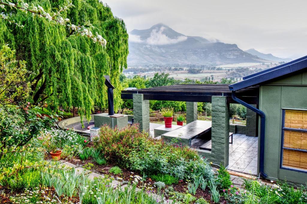 uma casa com um jardim com montanhas ao fundo em Golden View Luxury Self Catering em Clarens