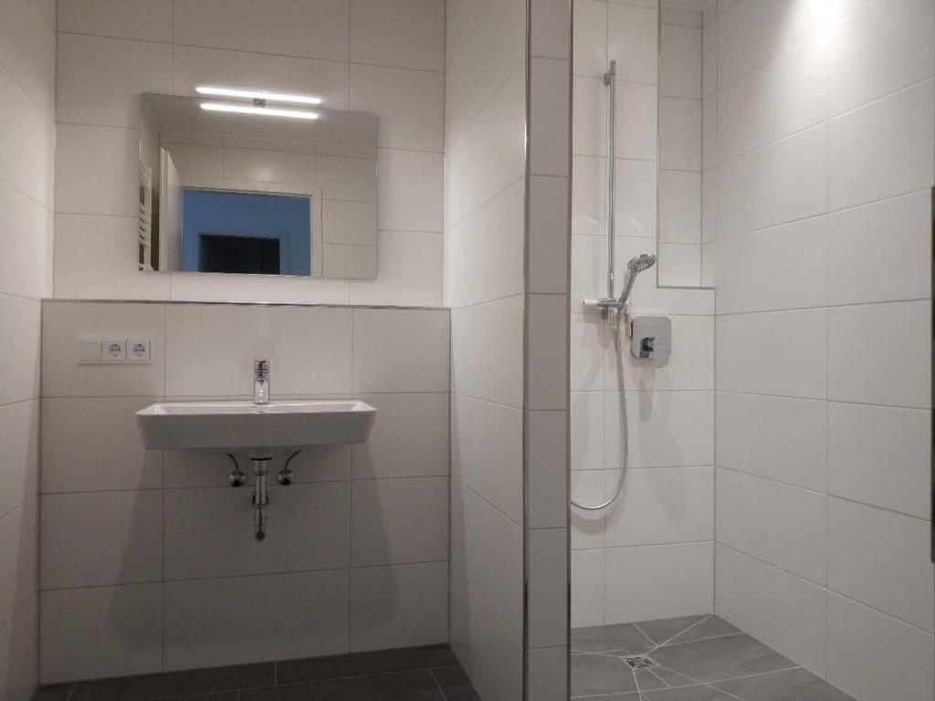 a white bathroom with a sink and a shower at Apartment "SUN" in Friedrichshafen