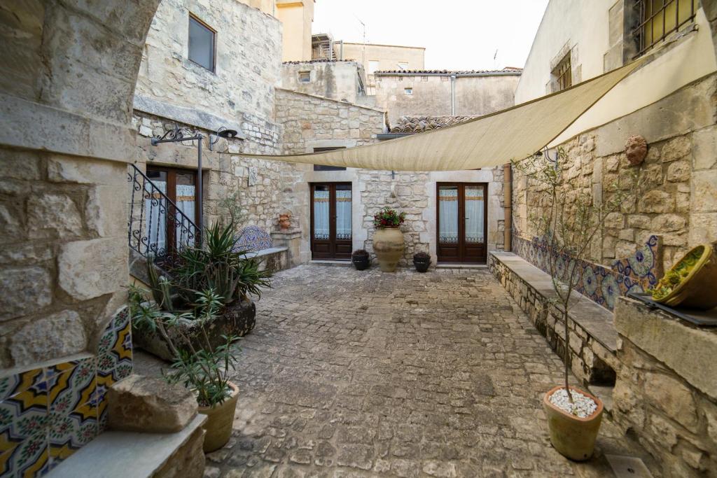 an alley in an old stone building with plants at Historic Modica in Modica