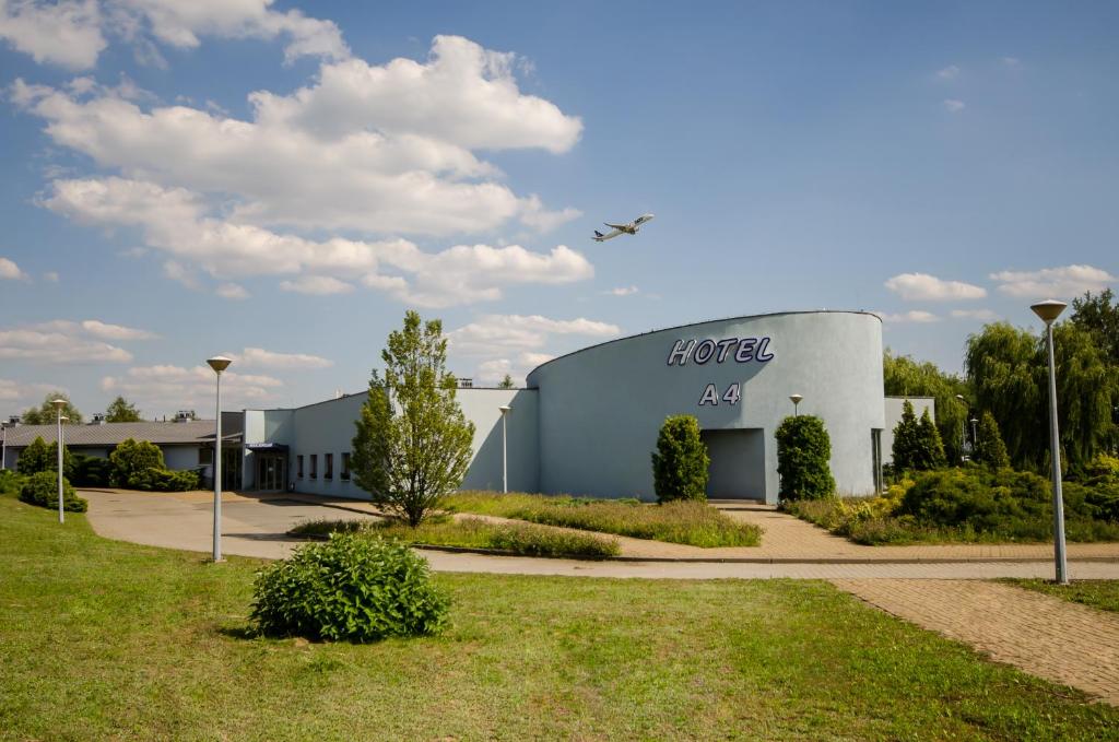 un avión sobrevolando un edificio con un hangar en HOTEL A4 Airport Kraków MOP Morawica, en Aleksandrowice